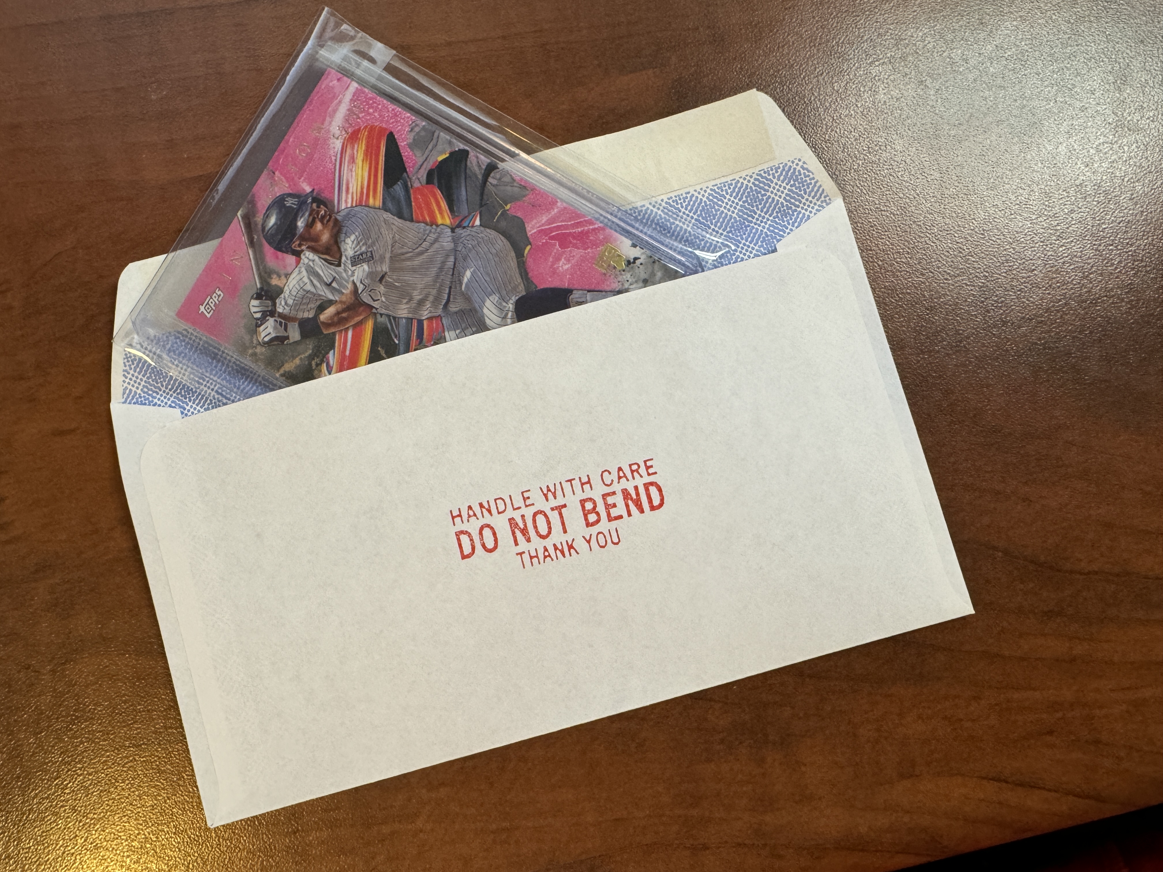 The fully protected baseball card being inserted into the envelope.